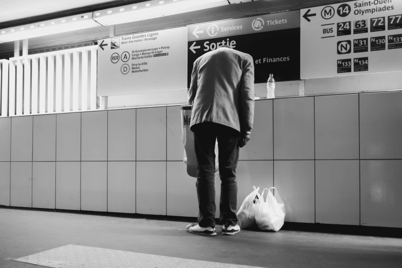 a person standing at a bus station next to a wall