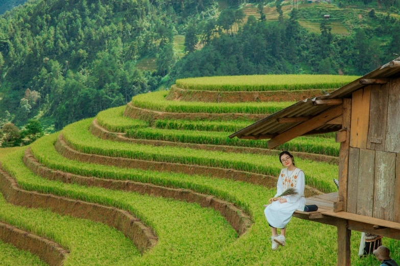 a woman sits on a bench near a very big grassy field