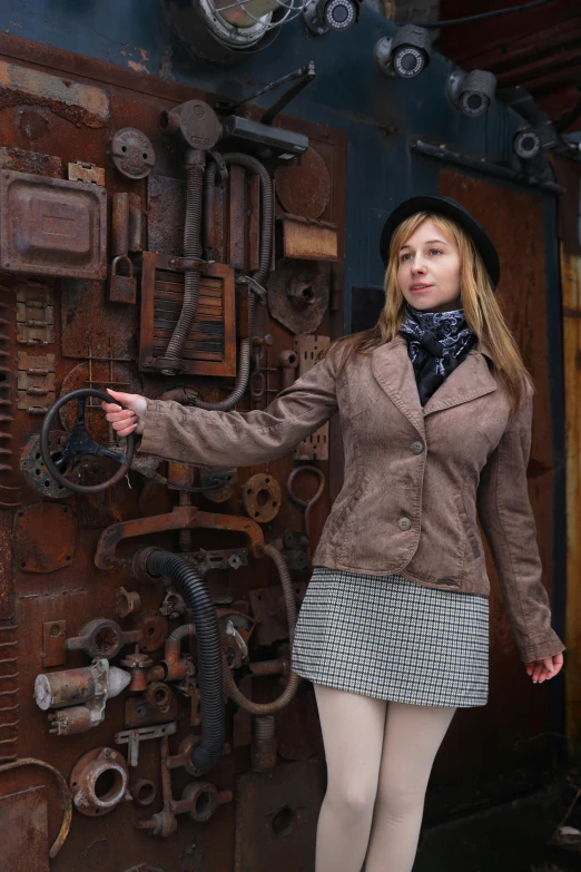 a woman with a coat and hat standing in front of a mechanical device