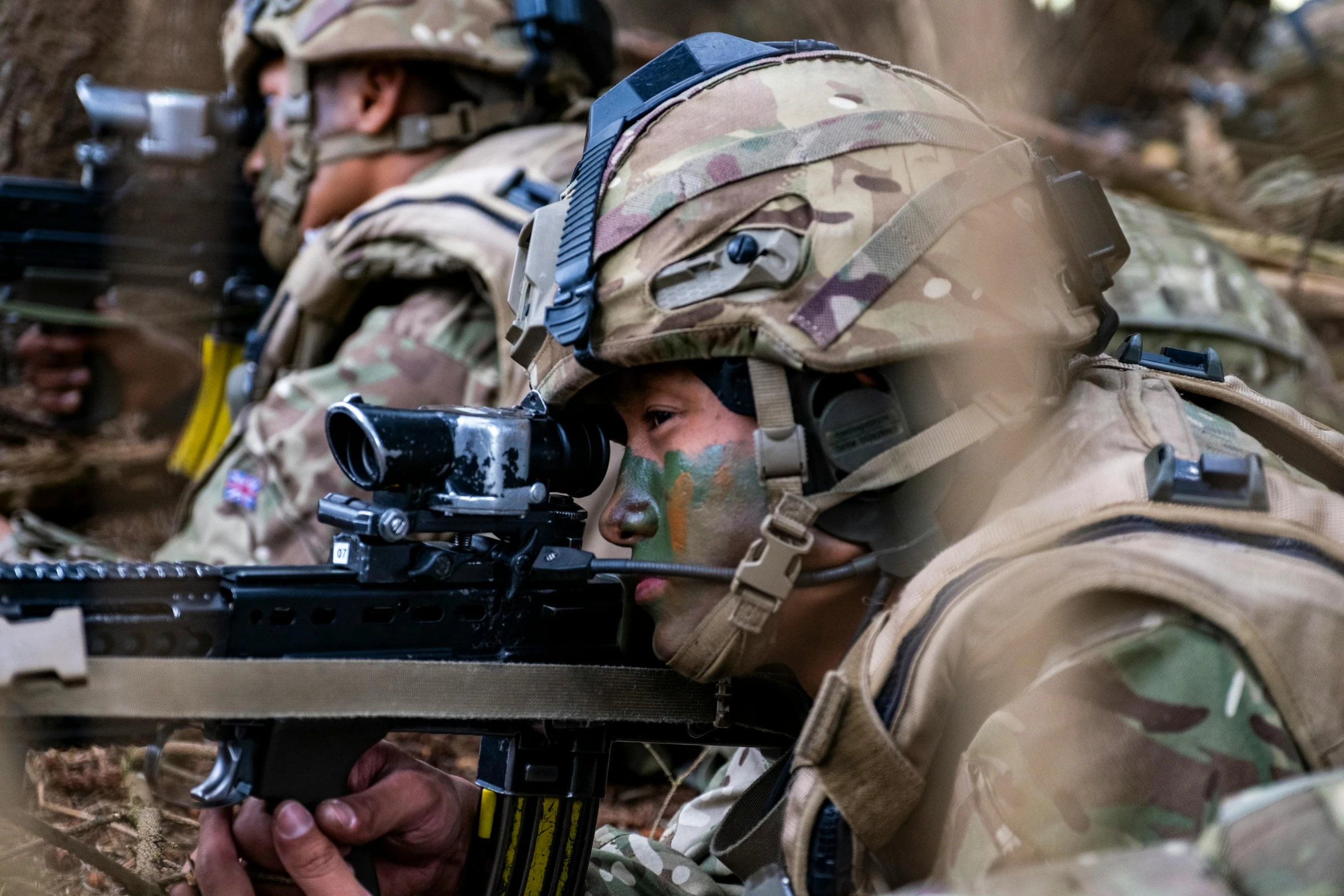 a soldier with a rifle being fitted to another man in uniform