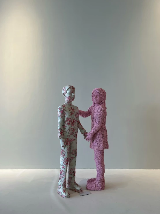 two sculptures made out of colored paper, each holding an infant