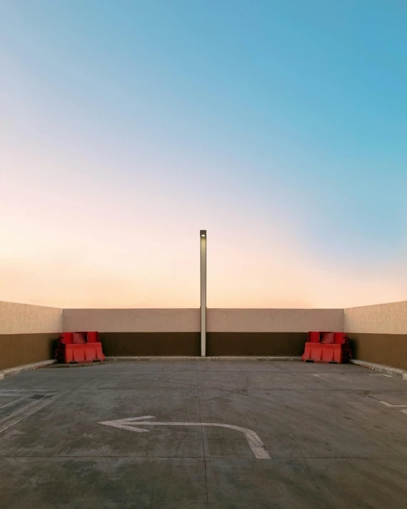 the empty parking lot with red seats and a tall pole