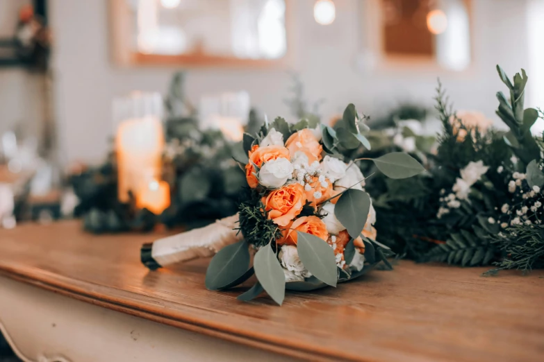 bouquet of flowers and greenery on table with candles