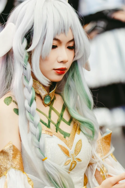 an asian woman in long, white hair and a id wearing green and gold makeup