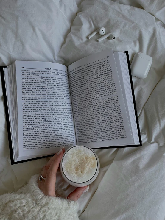 the person is reading a book and drinking a drink