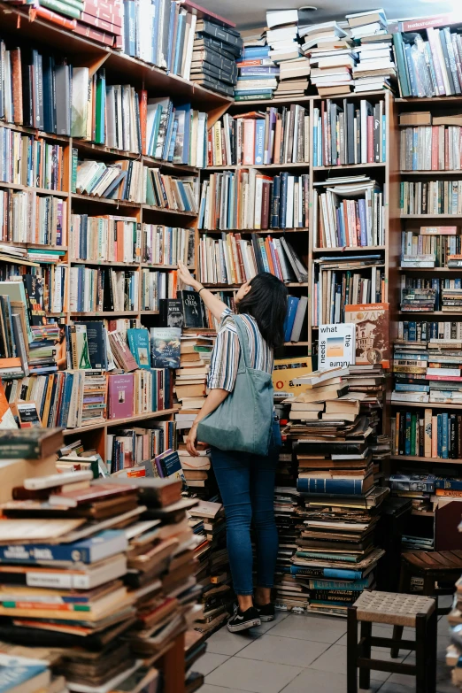 a woman is standing in the liry surrounded by a lot of books