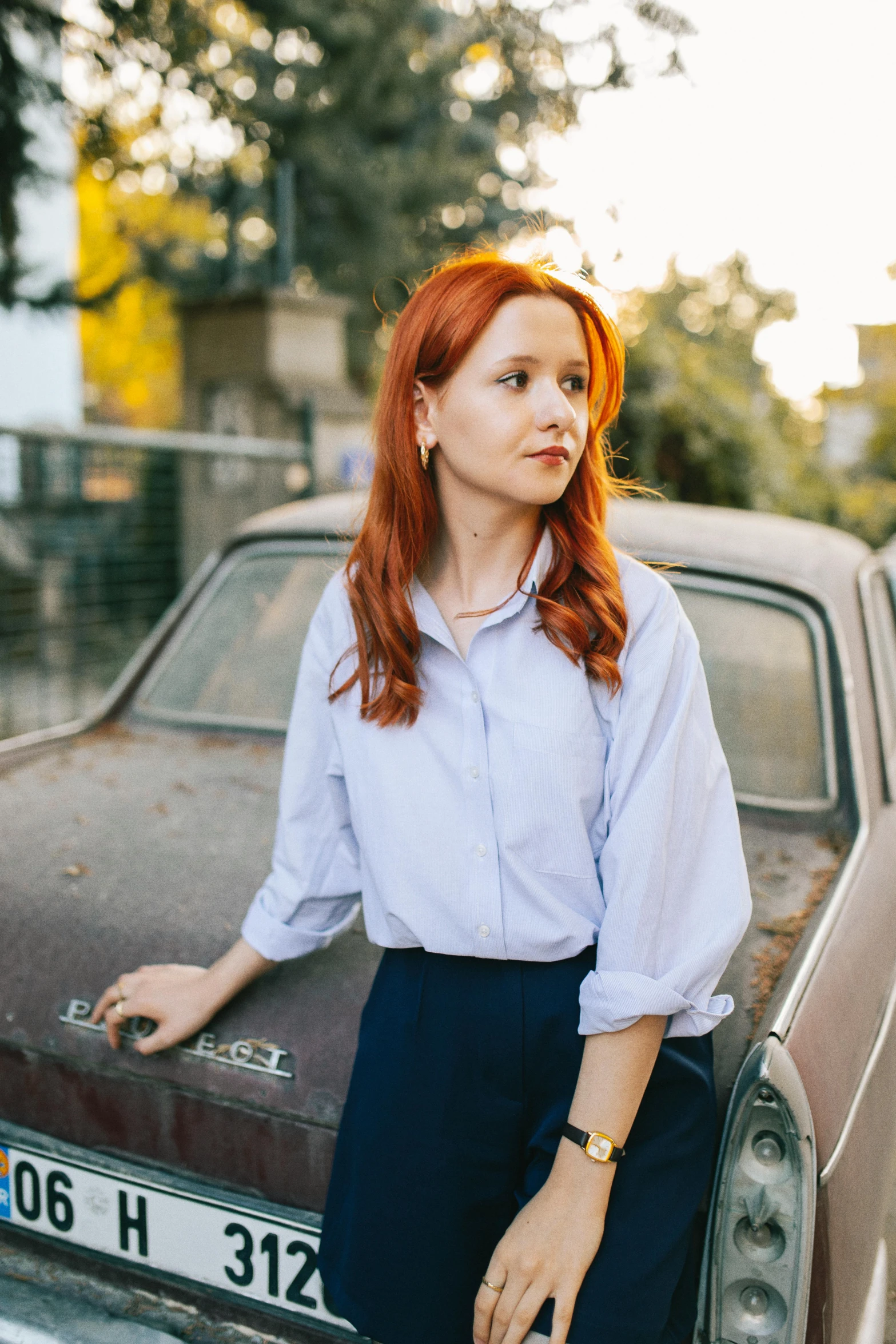 a woman leans on the hood of a car