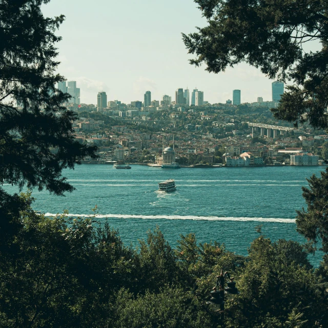 a boat out in the water with a city and trees behind it