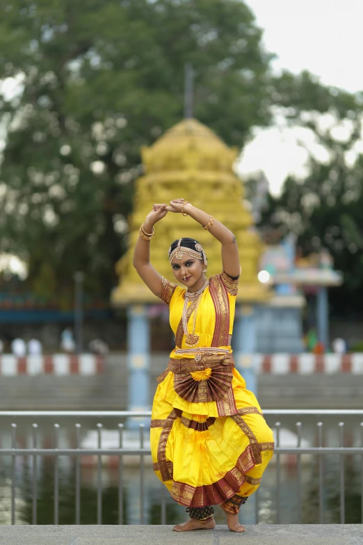 young woman wearing traditional yellow dress dancing at outdoor