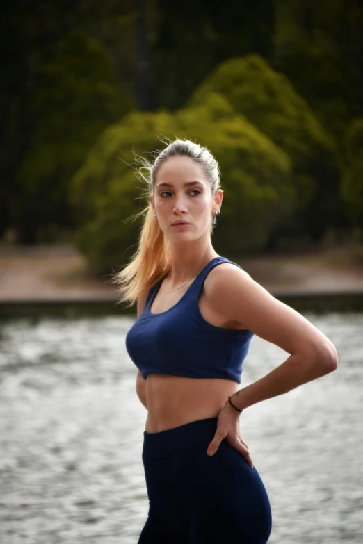 a woman in tight blue pants standing near water