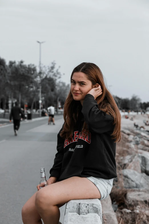 a pretty young lady holding a water bottle by the beach