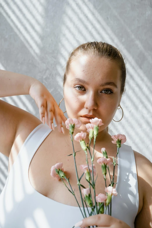 a woman with large earrings is smelling flowers