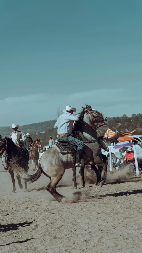 two men on horses ride through the dirt