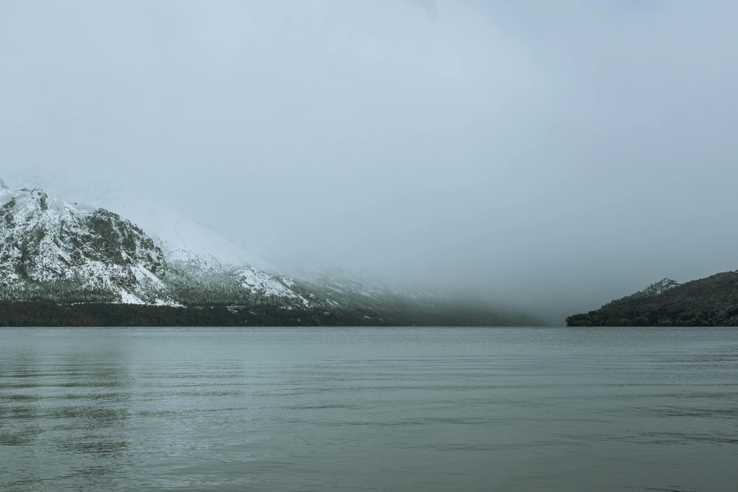 snow covered mountain ranges are rising over the water