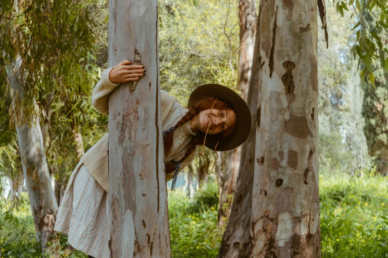 a woman leaning up against a tree in the forest