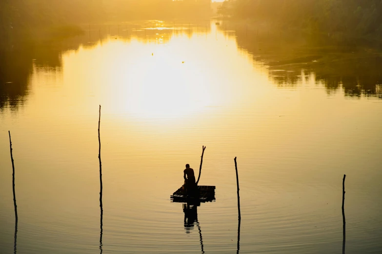 a person in a boat on a river at sunset