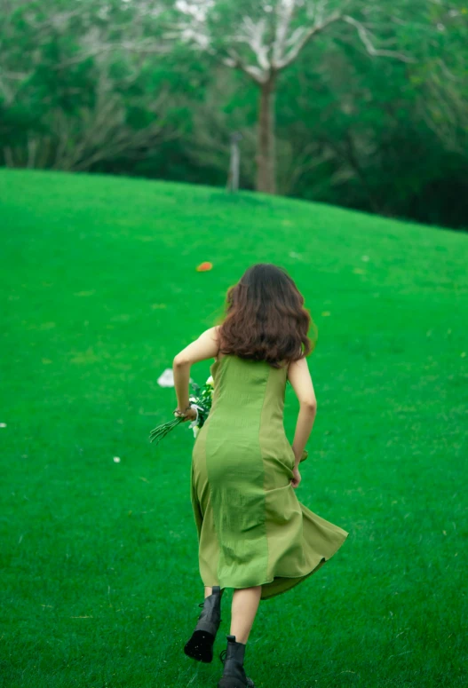 a woman wearing a green dress runs through a field