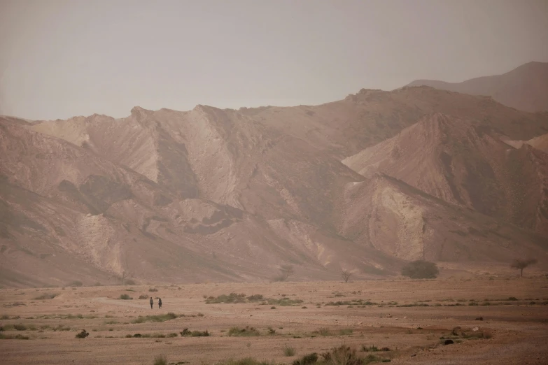 two people are standing in a large desert field