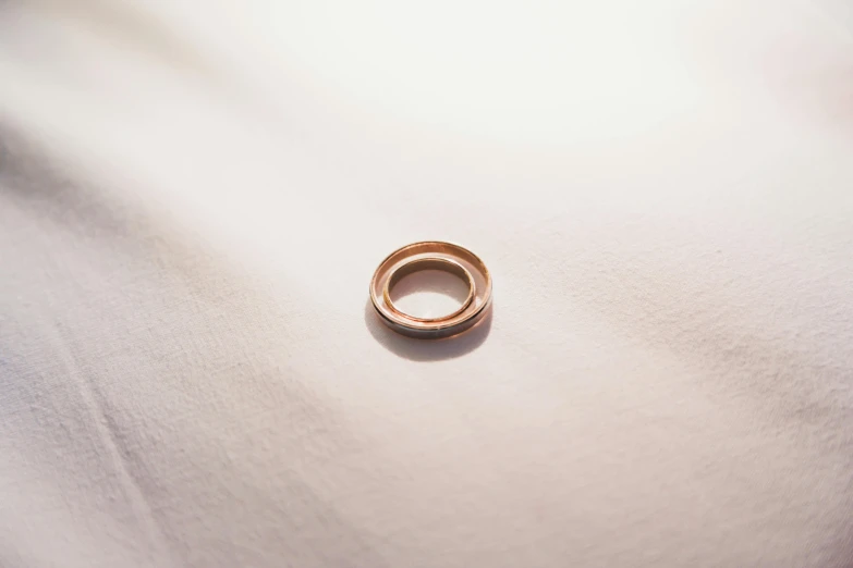 the ring sits on the white sheet with light shining in the background