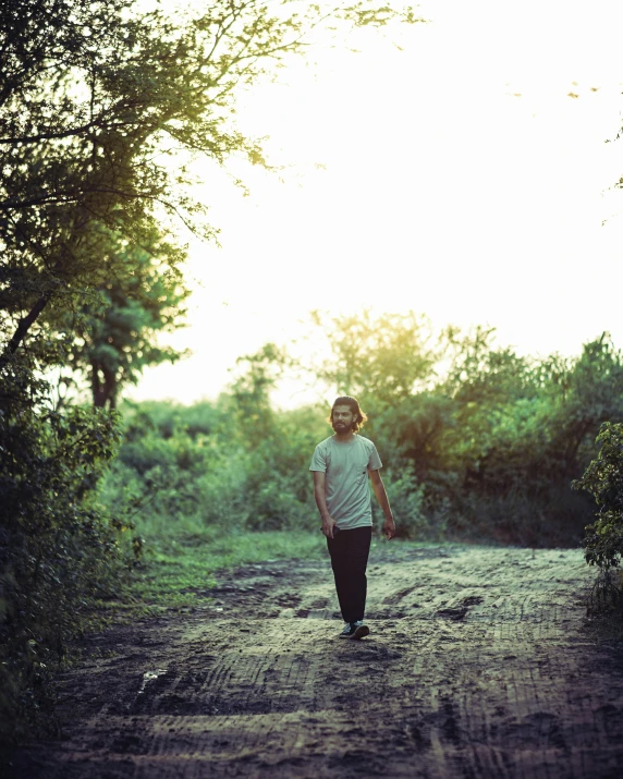a boy walking alone in the middle of a dirt road