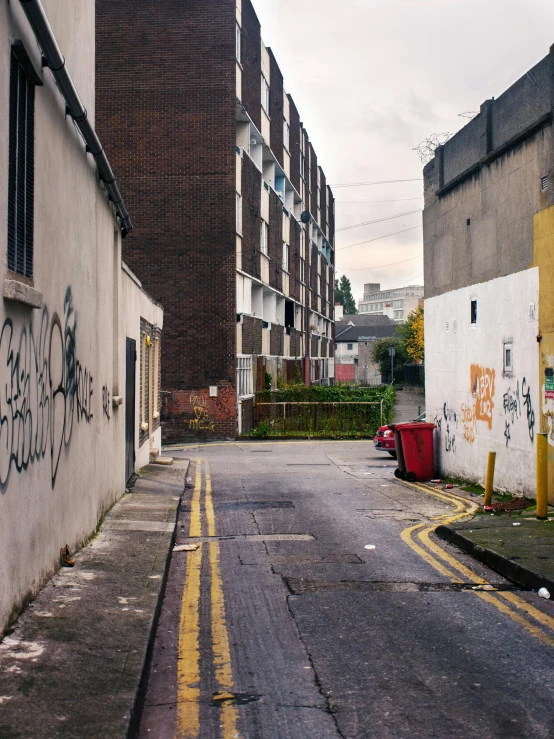 a empty road surrounded by tall buildings with graffiti