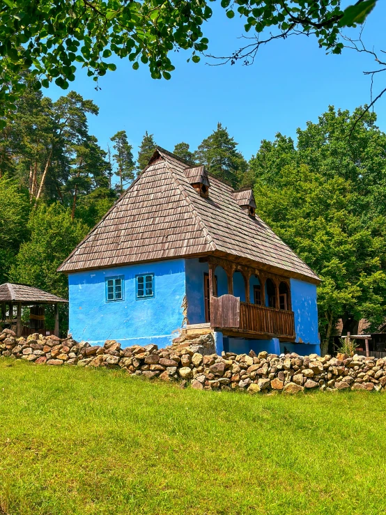 a very cute small blue house in a lush green field