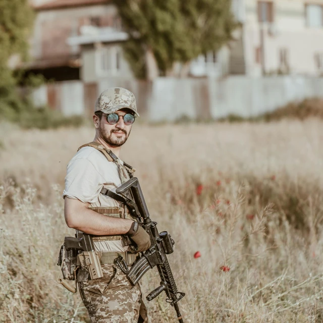 a man holding a rifle and posing in a field