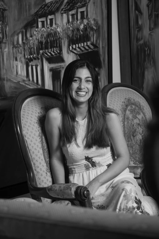 a girl sitting in a chair smiling for the camera