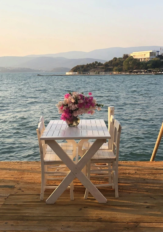 a table with some flowers is set on a dock