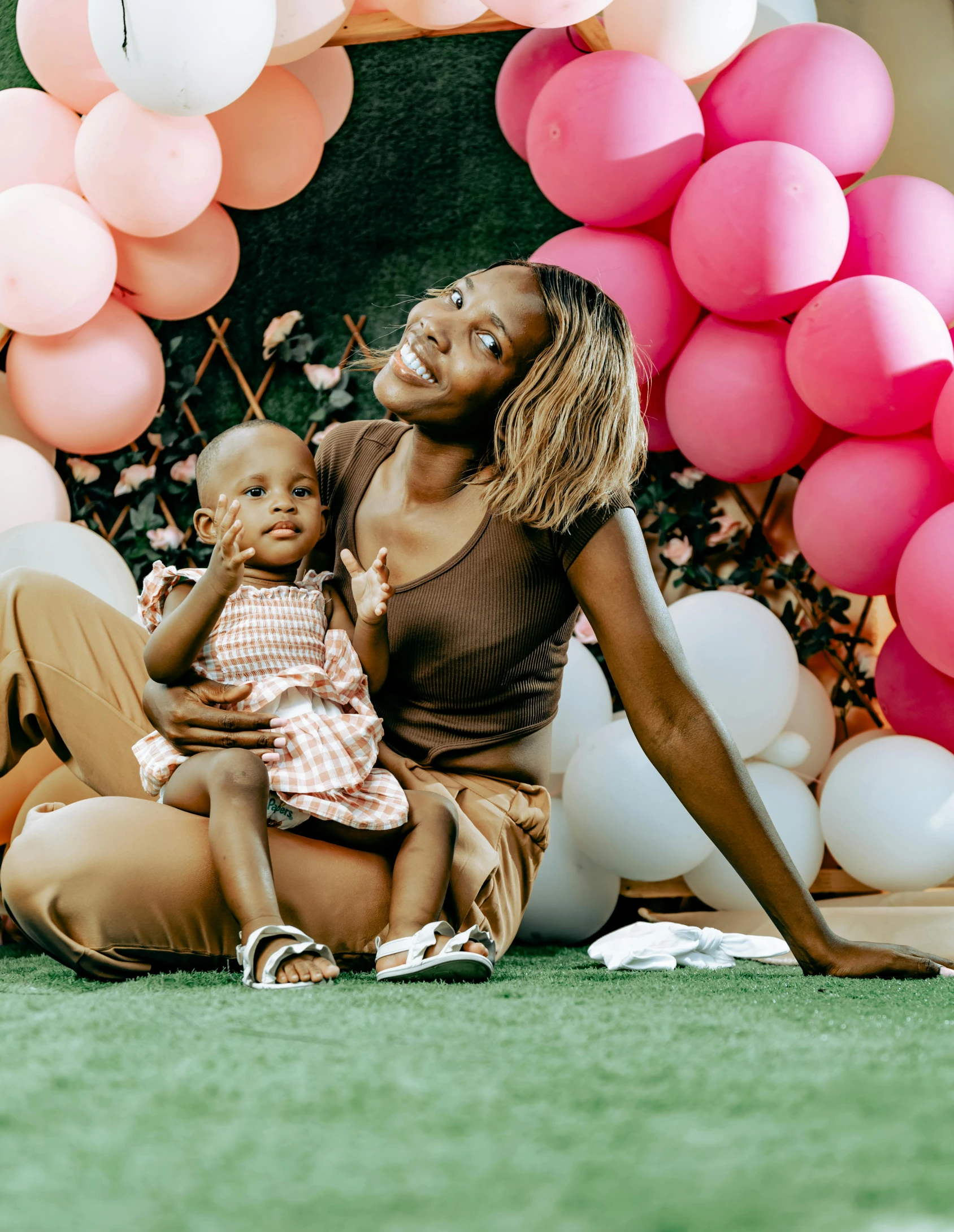 a woman sits in front of balloons with her baby