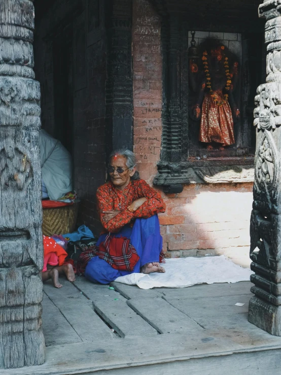 an old woman in red is sitting by her feet