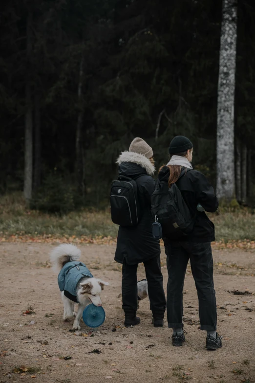 two people and a small dog standing outside