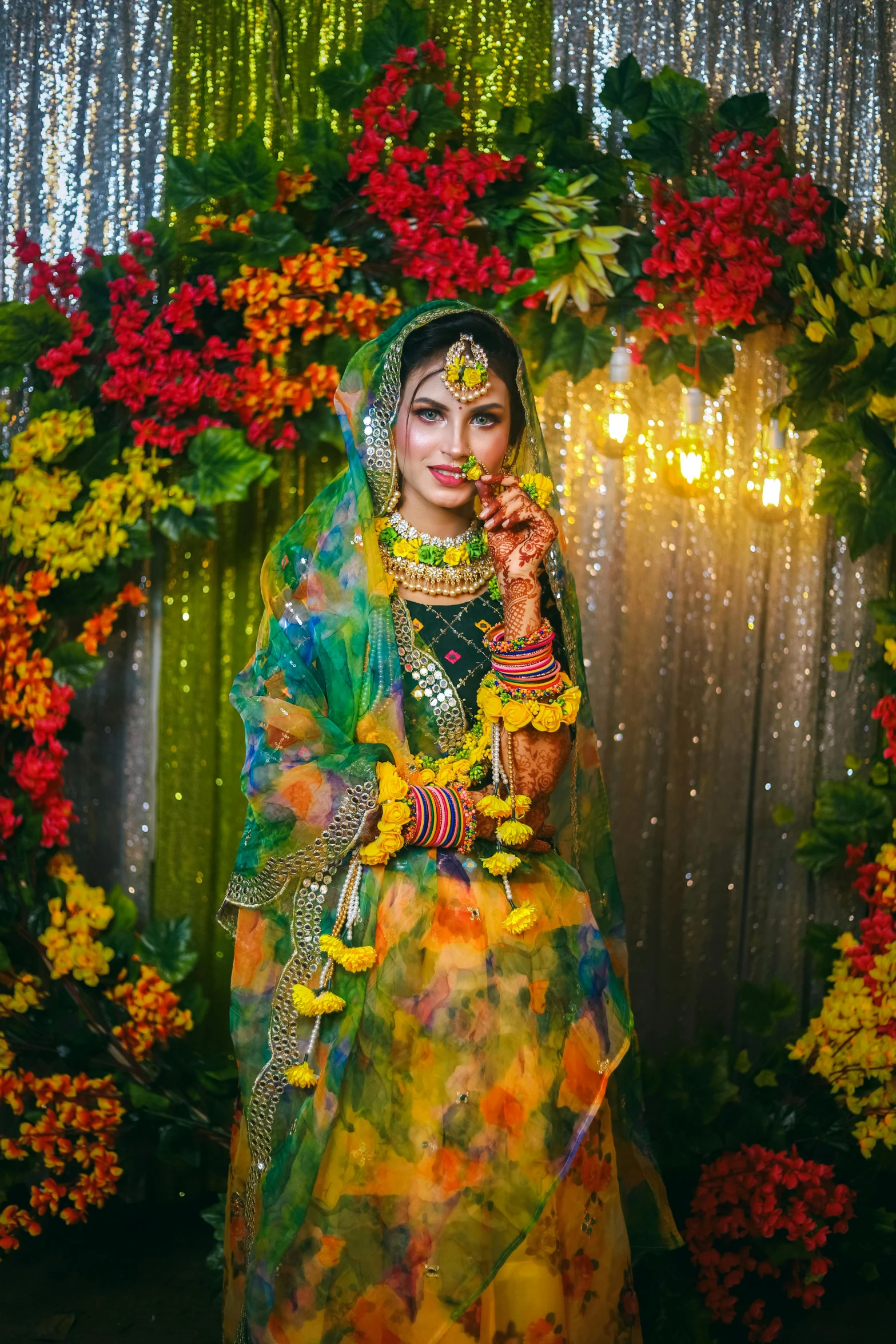 a woman in a colorful sari standing near a floral archway