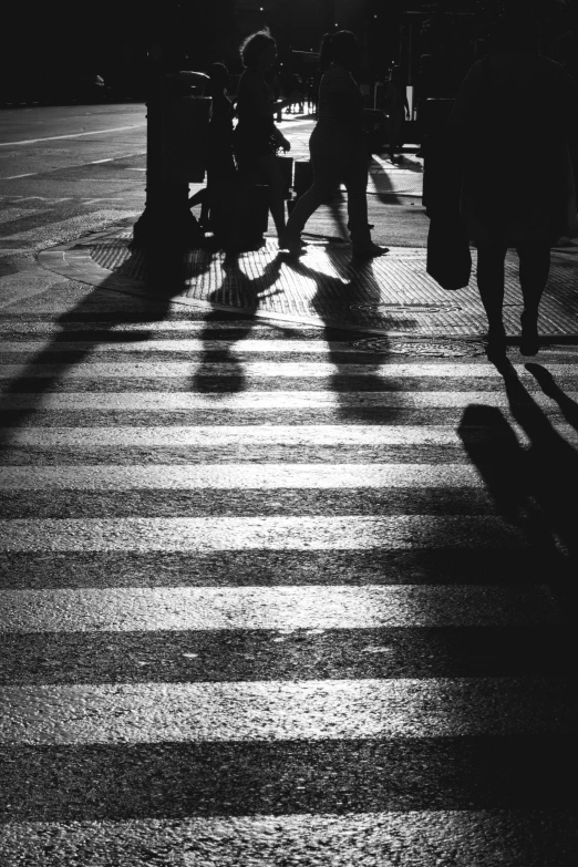 the shadows of pedestrians crossing a crosswalk