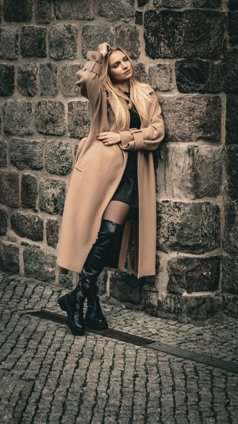 the young woman is leaning against a brick wall