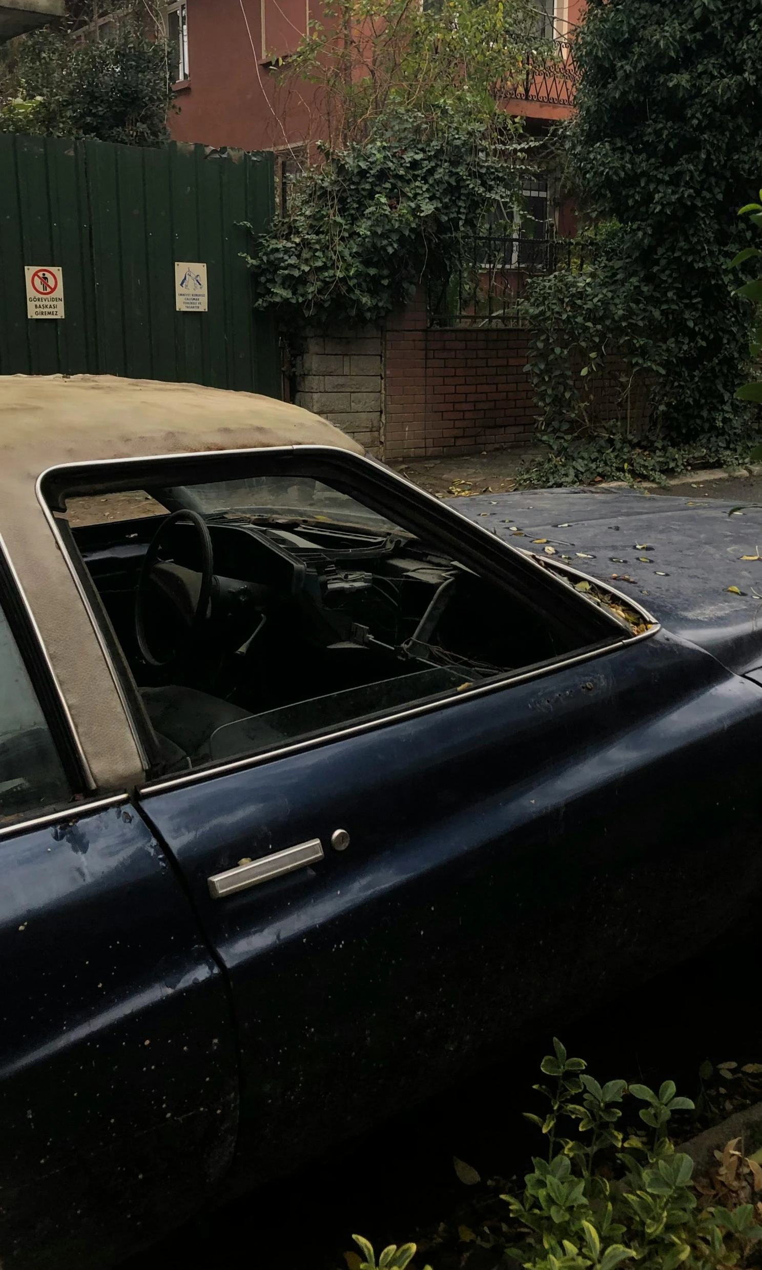 a car that is parked near bushes and a fence