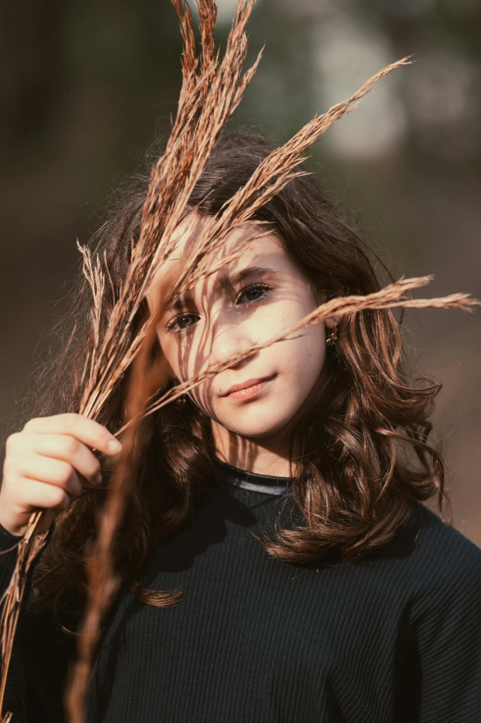 a child holding up dried grass with their hands