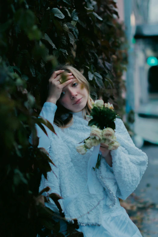 a young woman in white standing by a tree