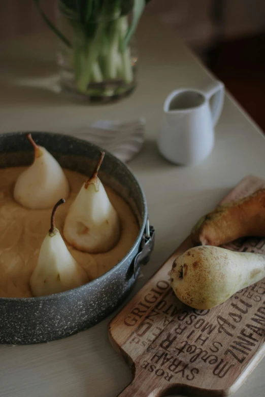 four pears, ginger, and a wooden spoon on a table