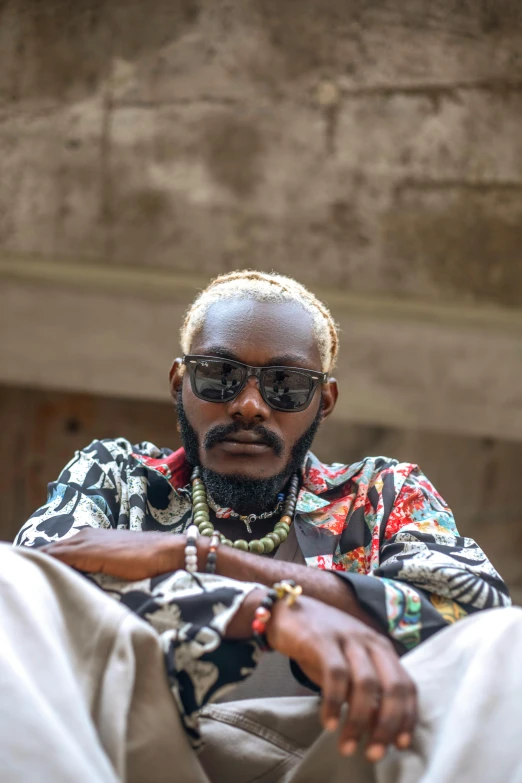 a man with a large headband, wearing sunglasses and an ornate patterned shirt