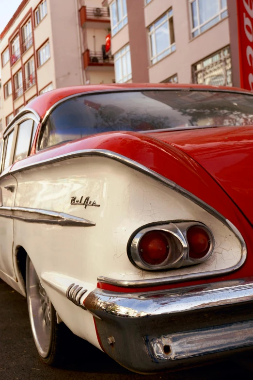 a old red and white car sitting in a street