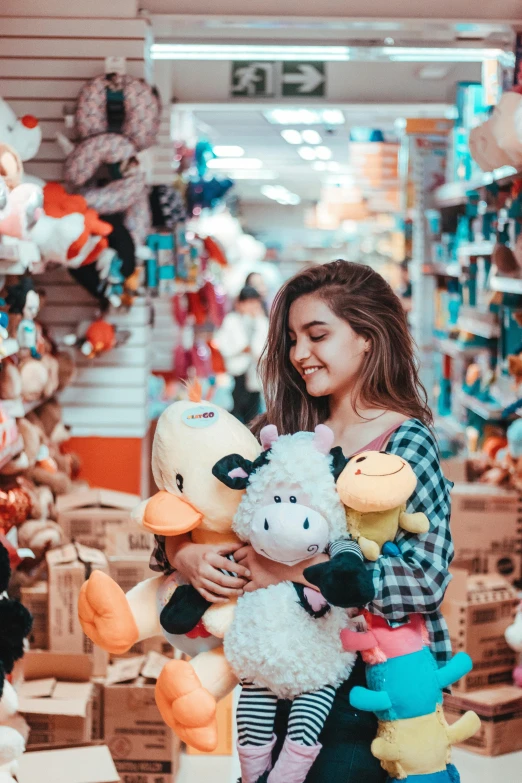 a girl holding stuffed animals in a store