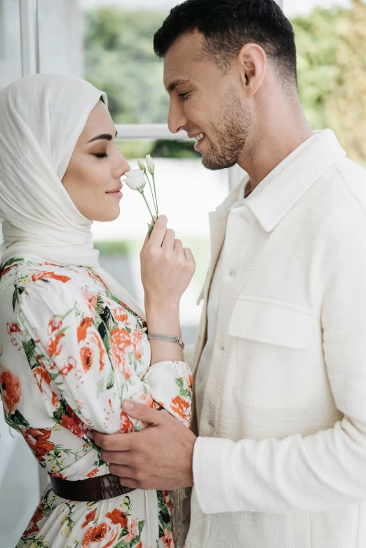 an engaged couple standing next to each other holding flowers