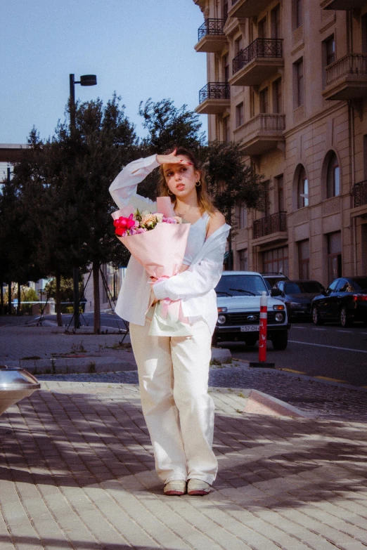 a girl in white walking down the street with flowers