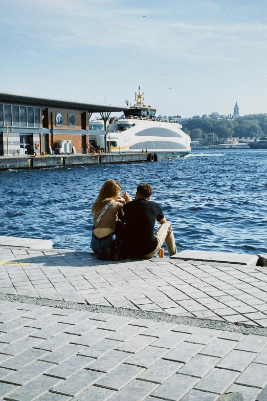 a couple of people are sitting on the side of the water