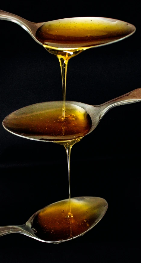 olive oil being poured into two spoons