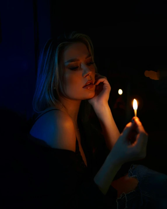 a woman holding a lit candle while sitting down