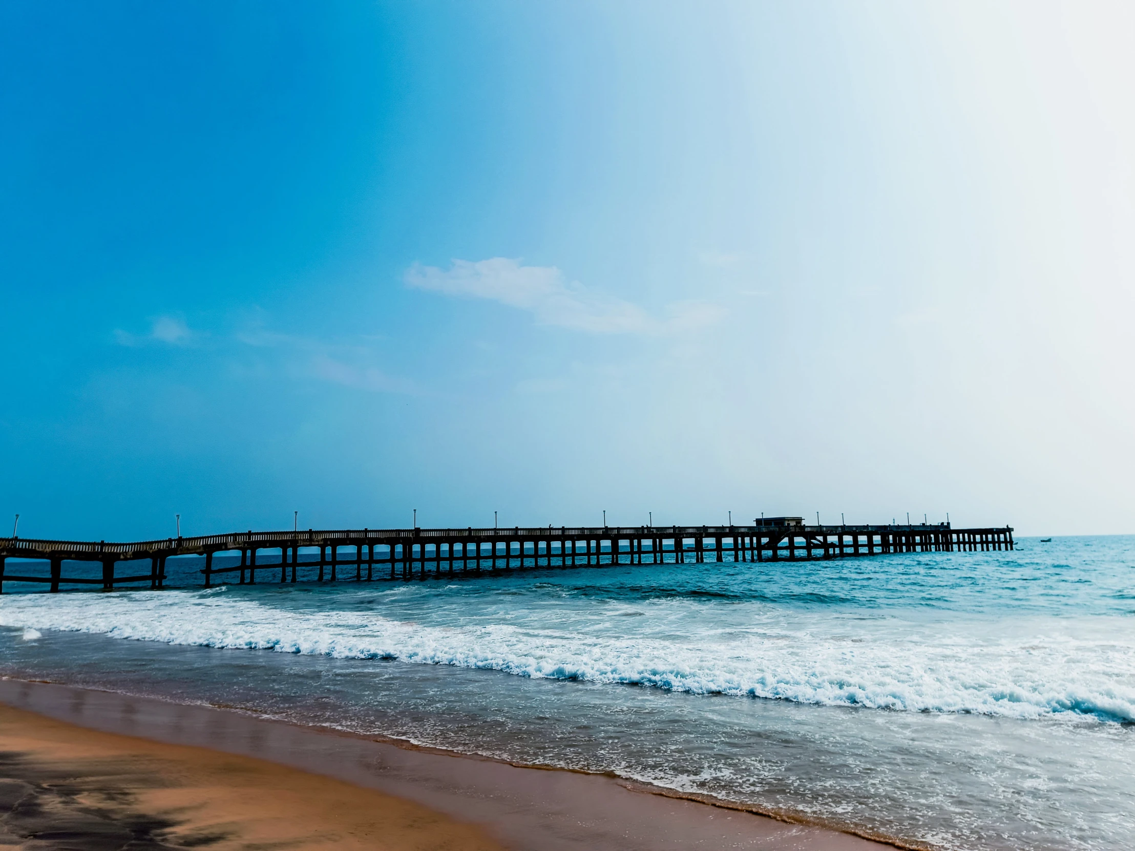 long jetty pier on the beach with clear sky above