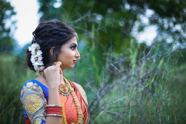 an indian woman standing in some grass with her head tilted to the side