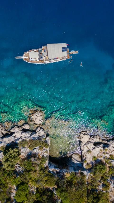 boats are floating in the clear water off of the shore